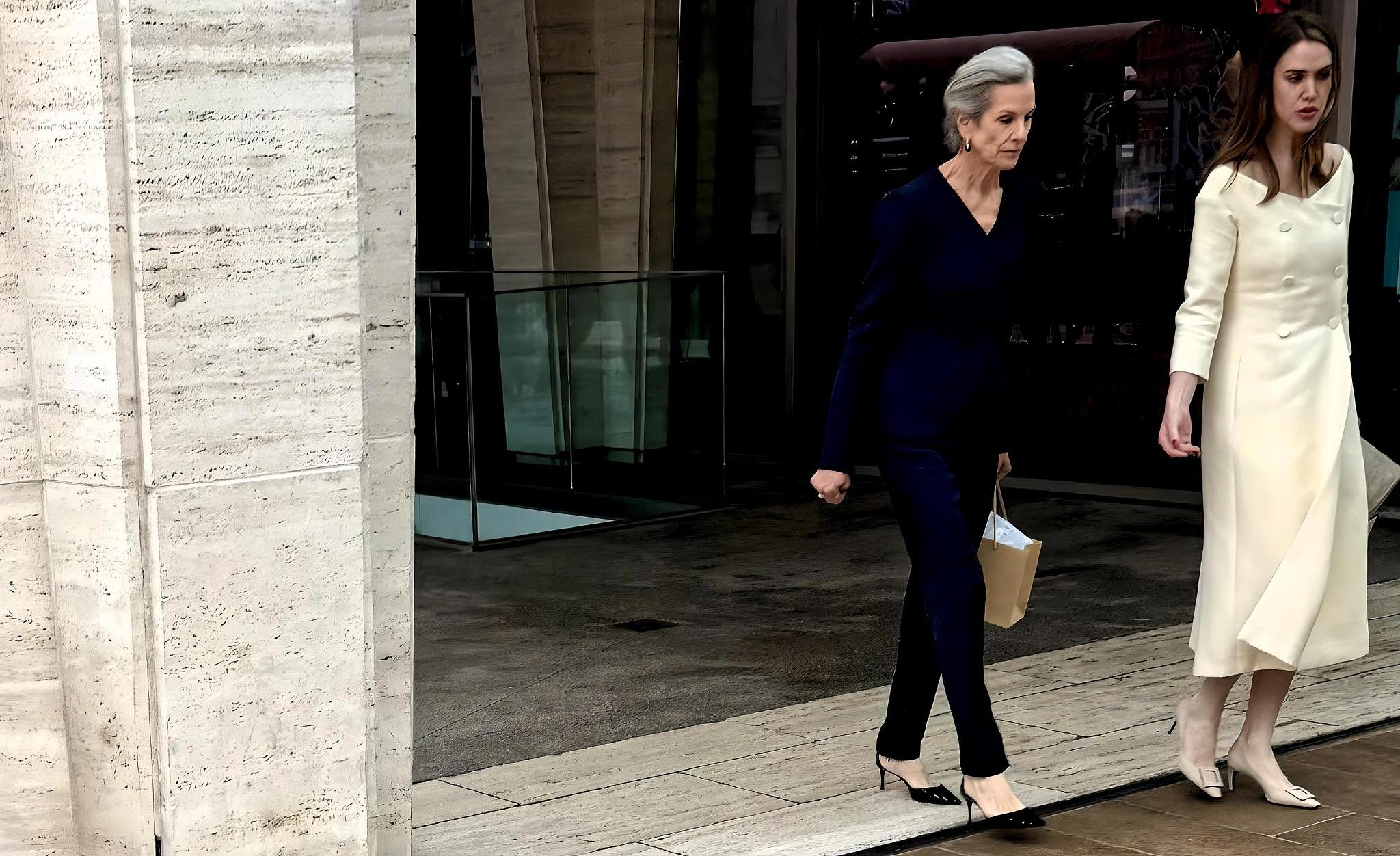 Two elegantly dressed women step out of a Manhattan building.