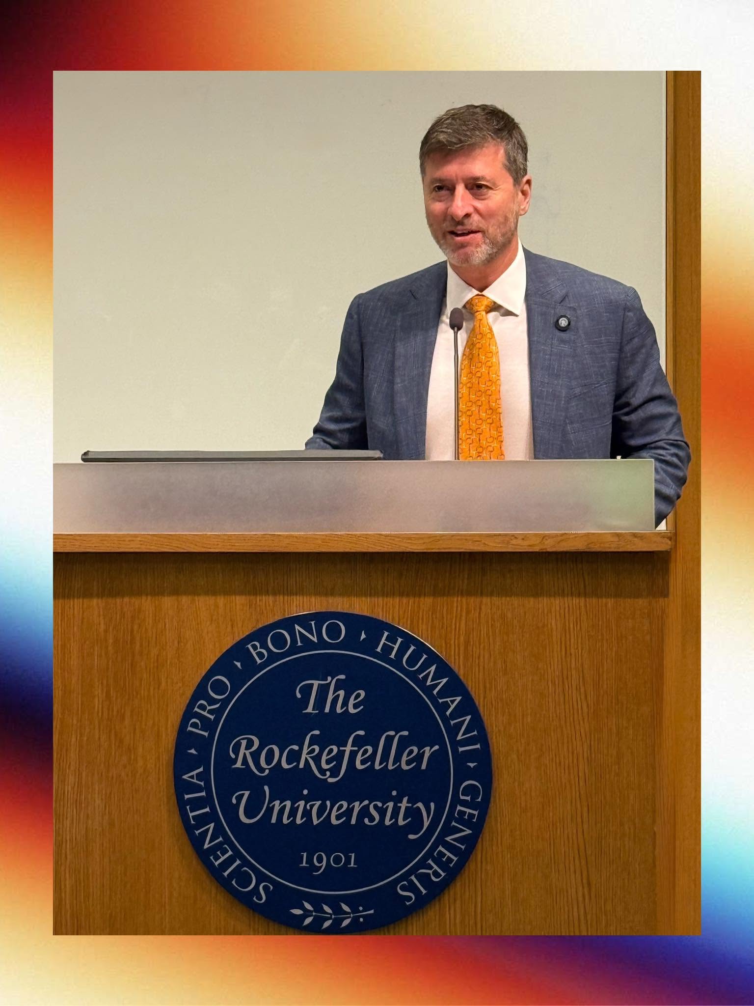 Edward Mermelstein speaks at a podium bearing the seal of Rockefeller University.