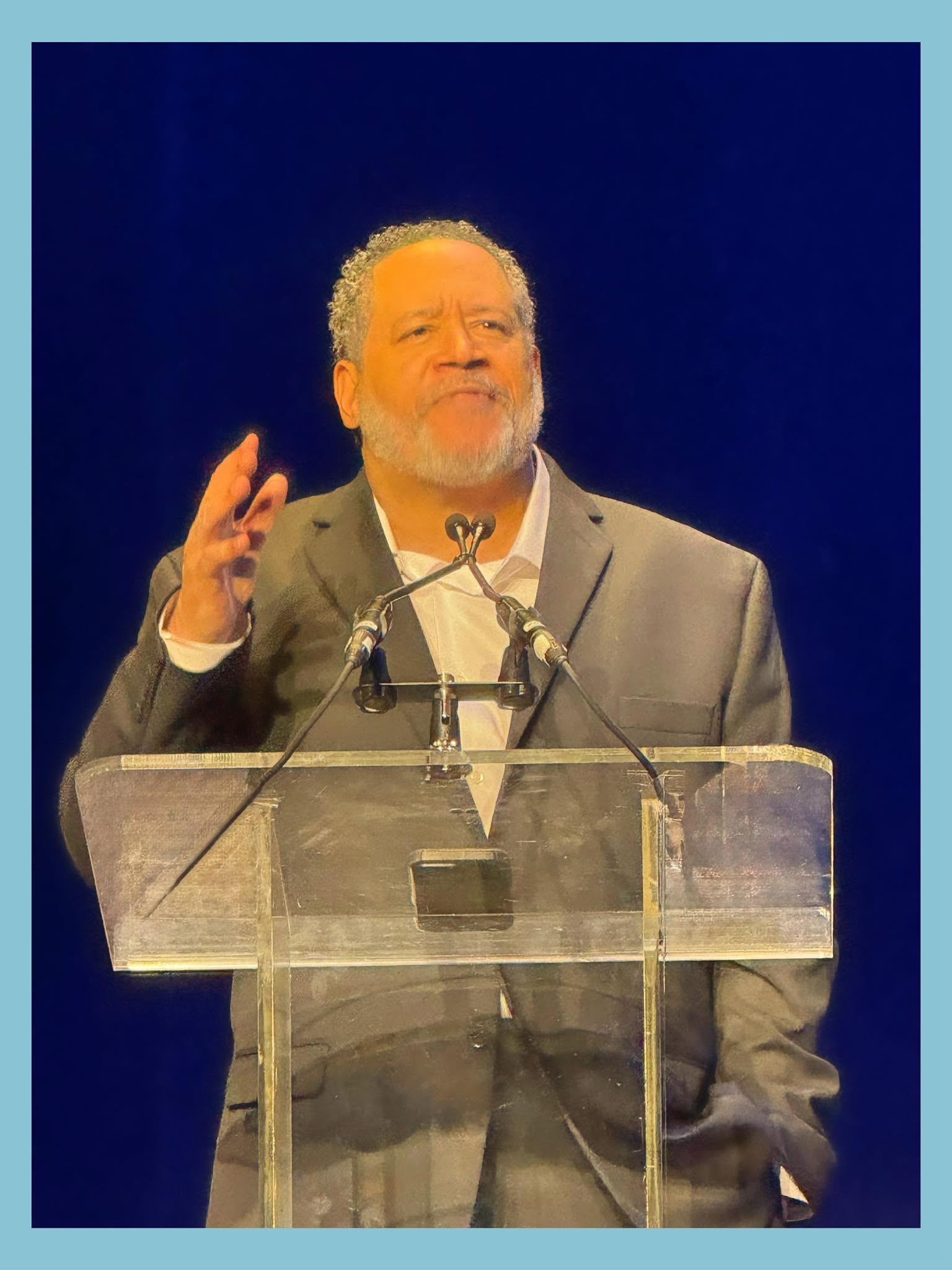 Michael Eric Dyson speaks at a podium, gesturing with one hand.