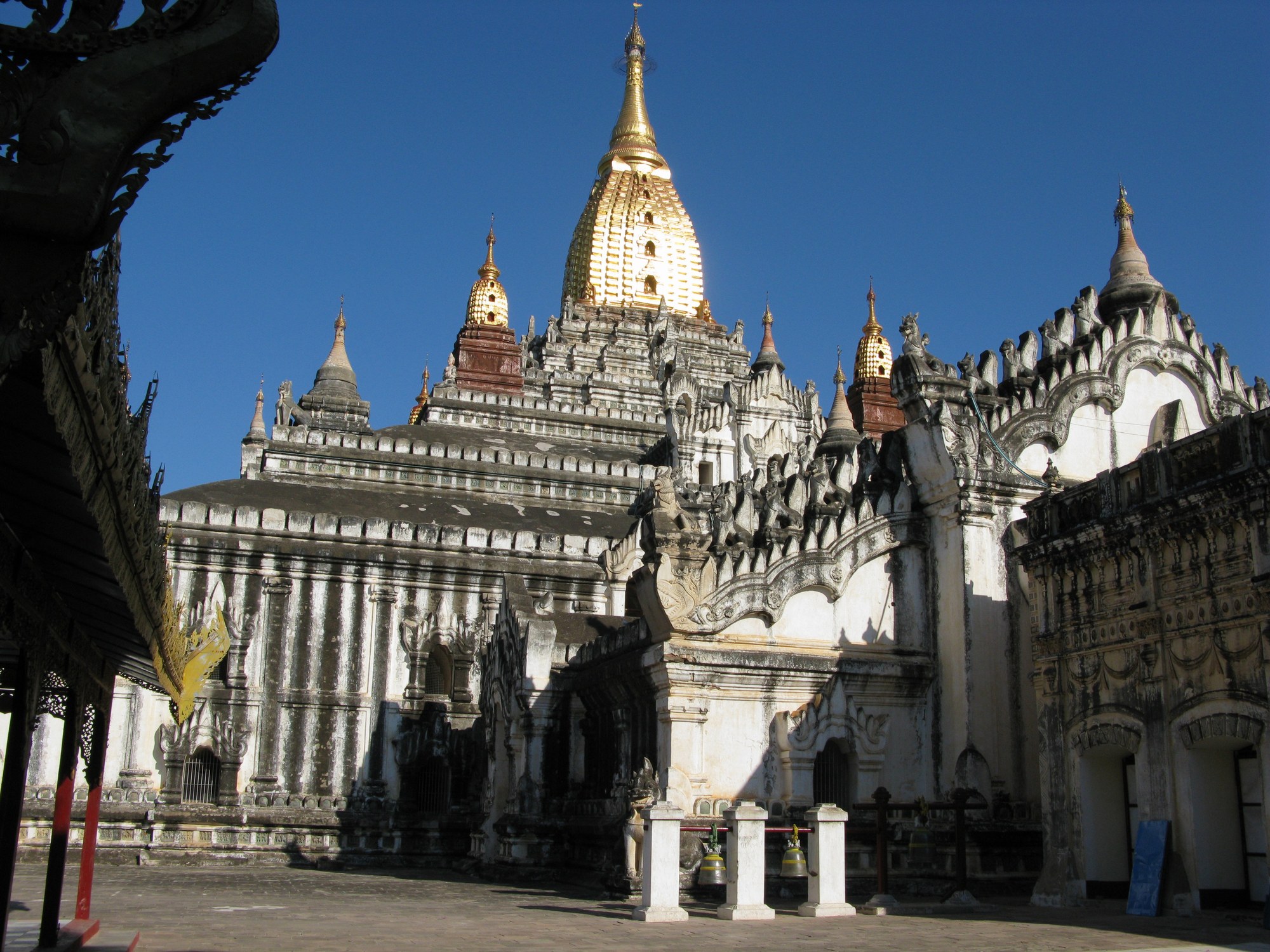 The white Ananda Temple in Bagan, Myanmar, with its tiered terraces and gilded spire against a blue sky
