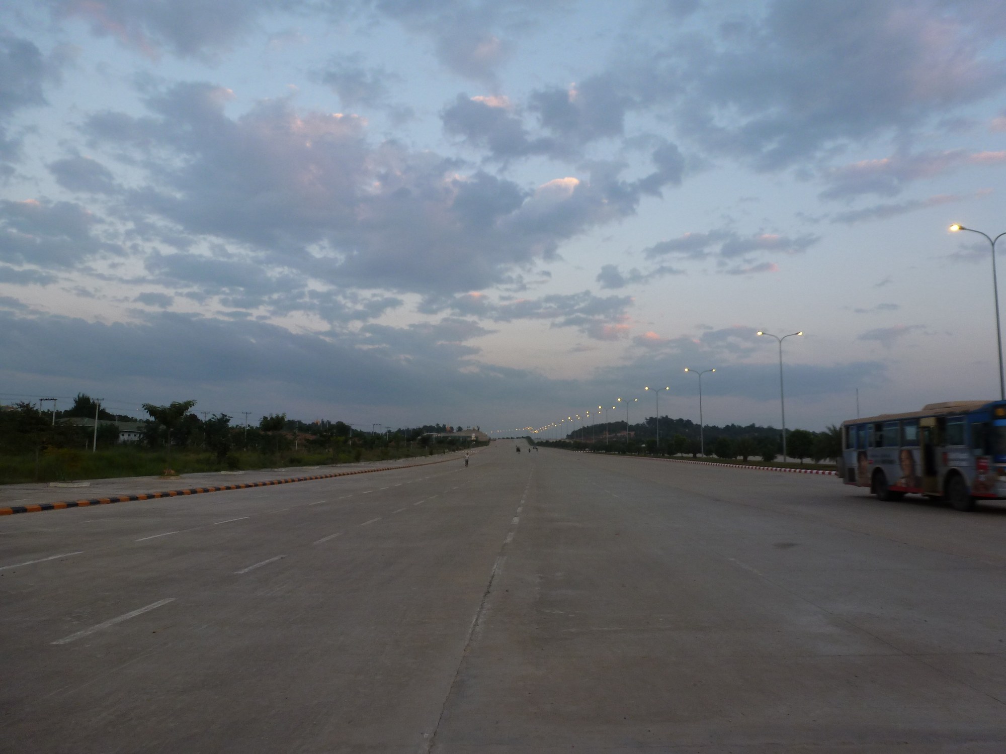 A wide, nearly empty multi-lane boulevard in Naypyitaw, Myanmar's capital, under an evening sky