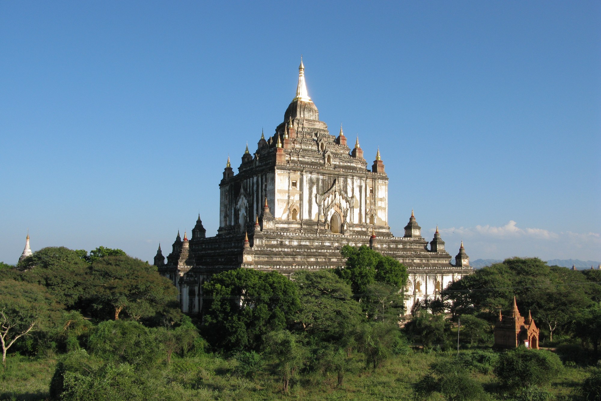 Thatbyinnyu Temple rising above trees on the Bagan plain, its pale terraces topped by a spire