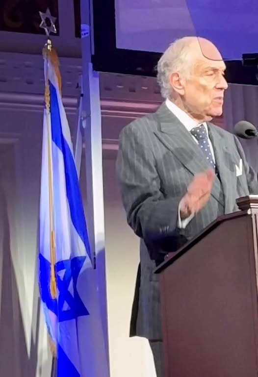 Ronald Lauder speaks at a podium beside an Israeli flag.