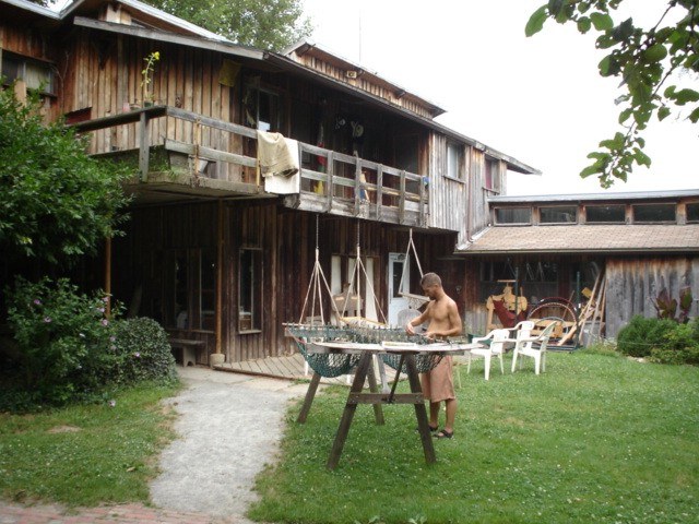 Hammock inweaving at Twin Oaks (community building with porch, member at loom)