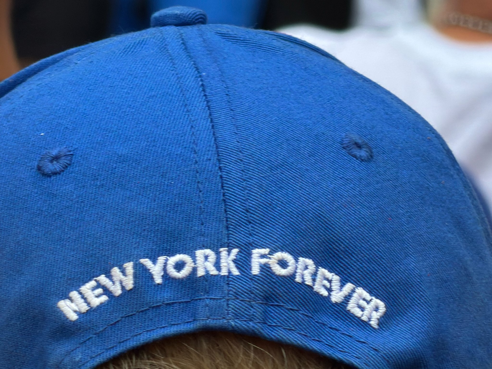 The back of a blue baseball cap embroidered NEW YORK FOREVER in white thread