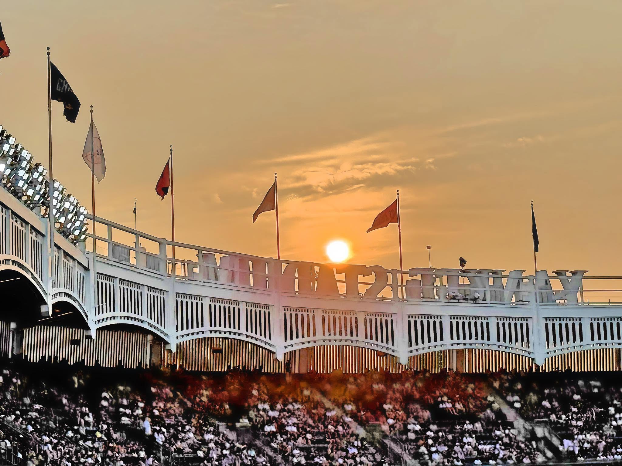 Sunset behind the frieze and flags at Yankee Stadium, July 2025