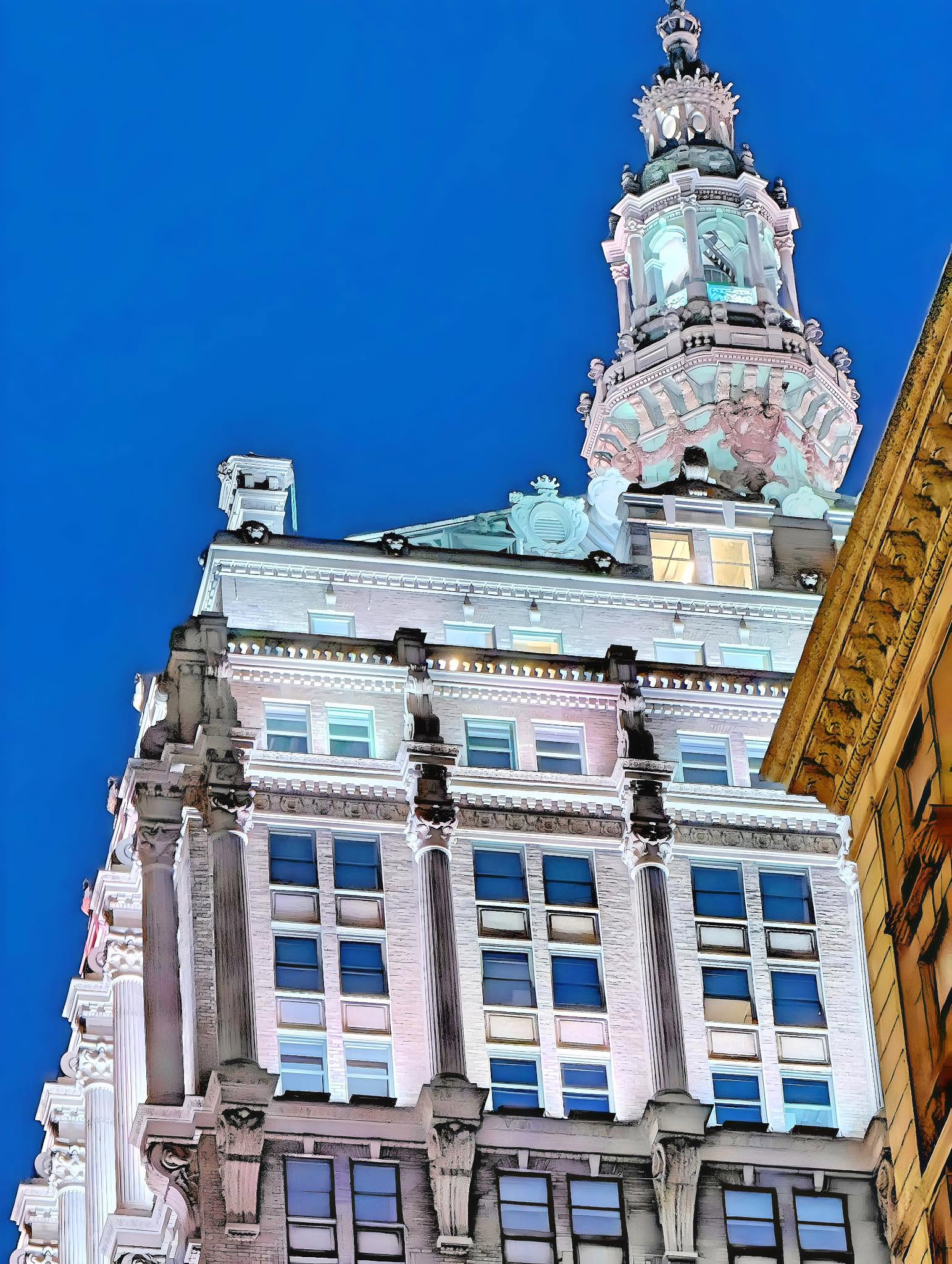 The illuminated tower of the Helmsley Building rising against a deep blue night sky in Manhattan.