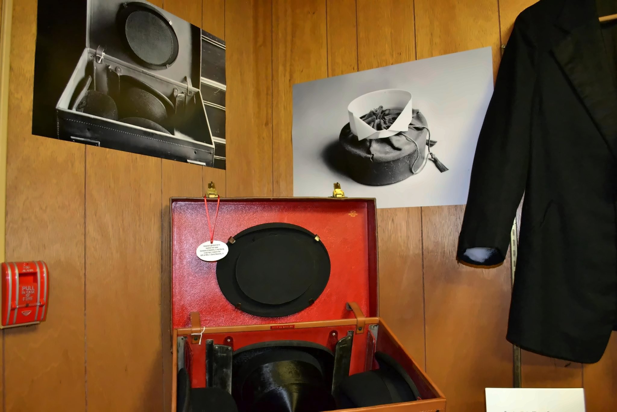 The hat case open on its stand, a tailcoat hanging beside it.