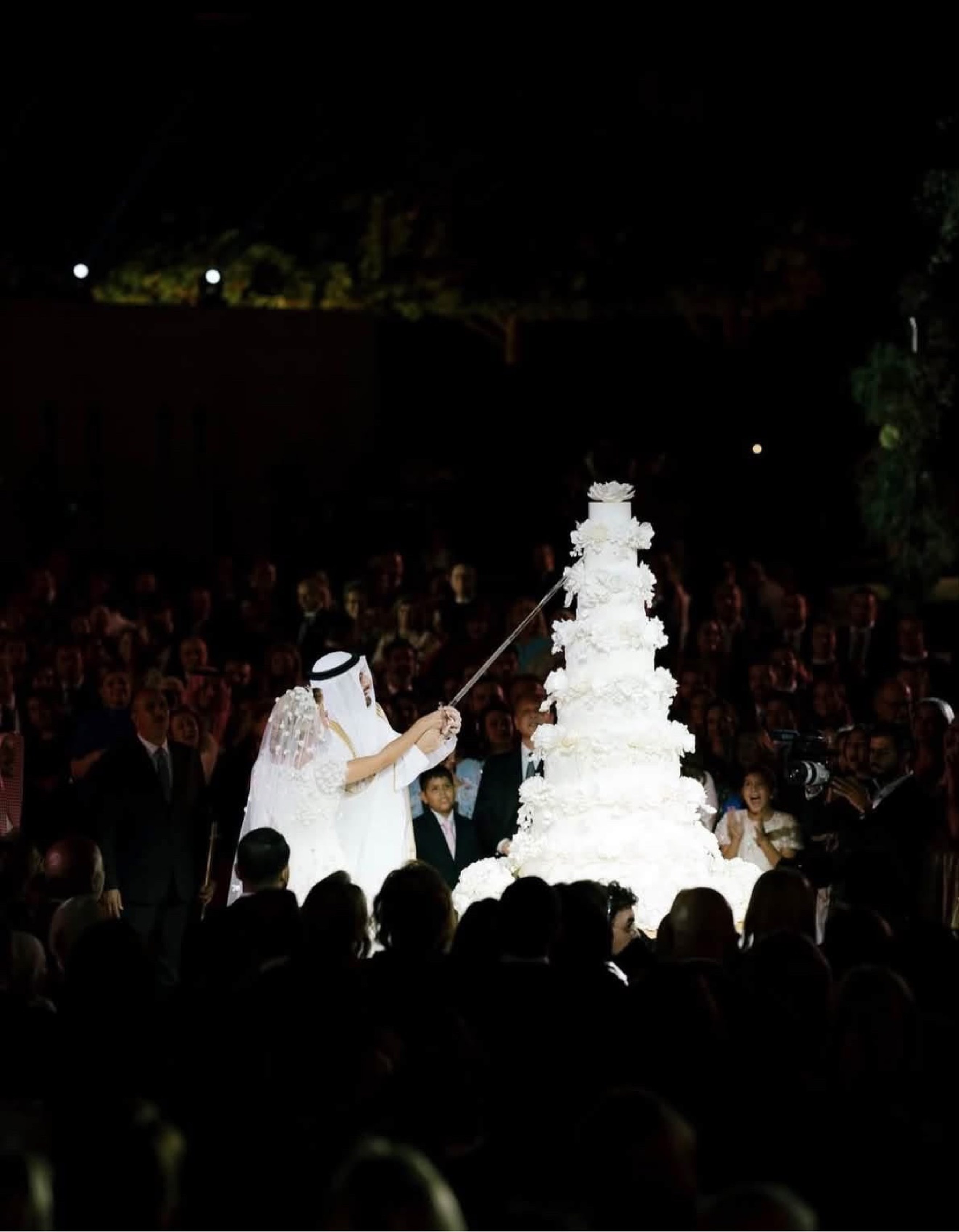 Princess Sara bint Faisal and Ali Murabet Al Sawaf cutting their wedding cake with a sword