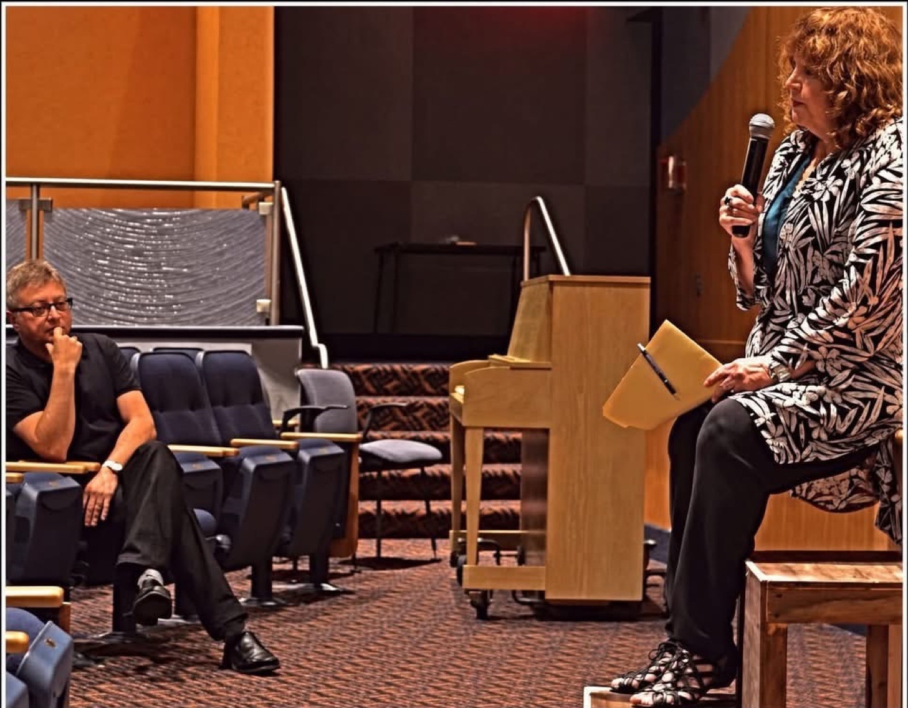 Toby Shylit Mack introduces her friend Michael E. Uslan at the Axelrod Performing Arts Center in Deal Park — microphone in hand, yellow legal pad at the ready — on the night he brought The Boy Who Loved Batman home.